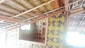 A room with a thatched roof, woven wall panels, and a window with a wooden frame. - Masipai Guest House (Tingwon Island)