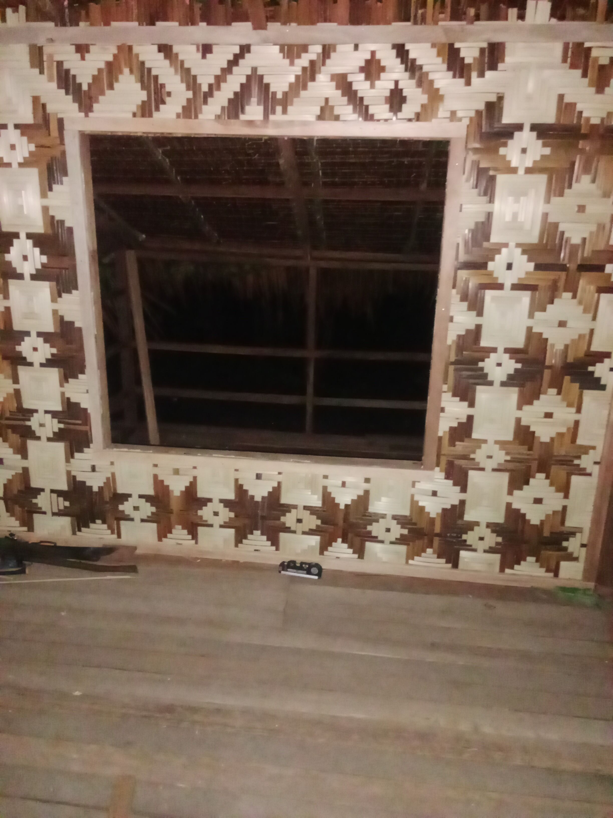 A room with a large window, patterned wall tiles, and a wooden floor.