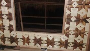 A room with a large window, patterned wall tiles, and a wooden floor.