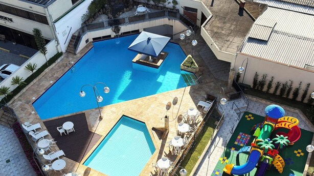 Un área de piscina en la azotea con múltiples piscinas, tumbonas y una zona de juegos infantiles.