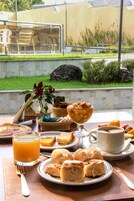Una mesa de desayuno con diversos alimentos y un vaso de jugo de naranja.