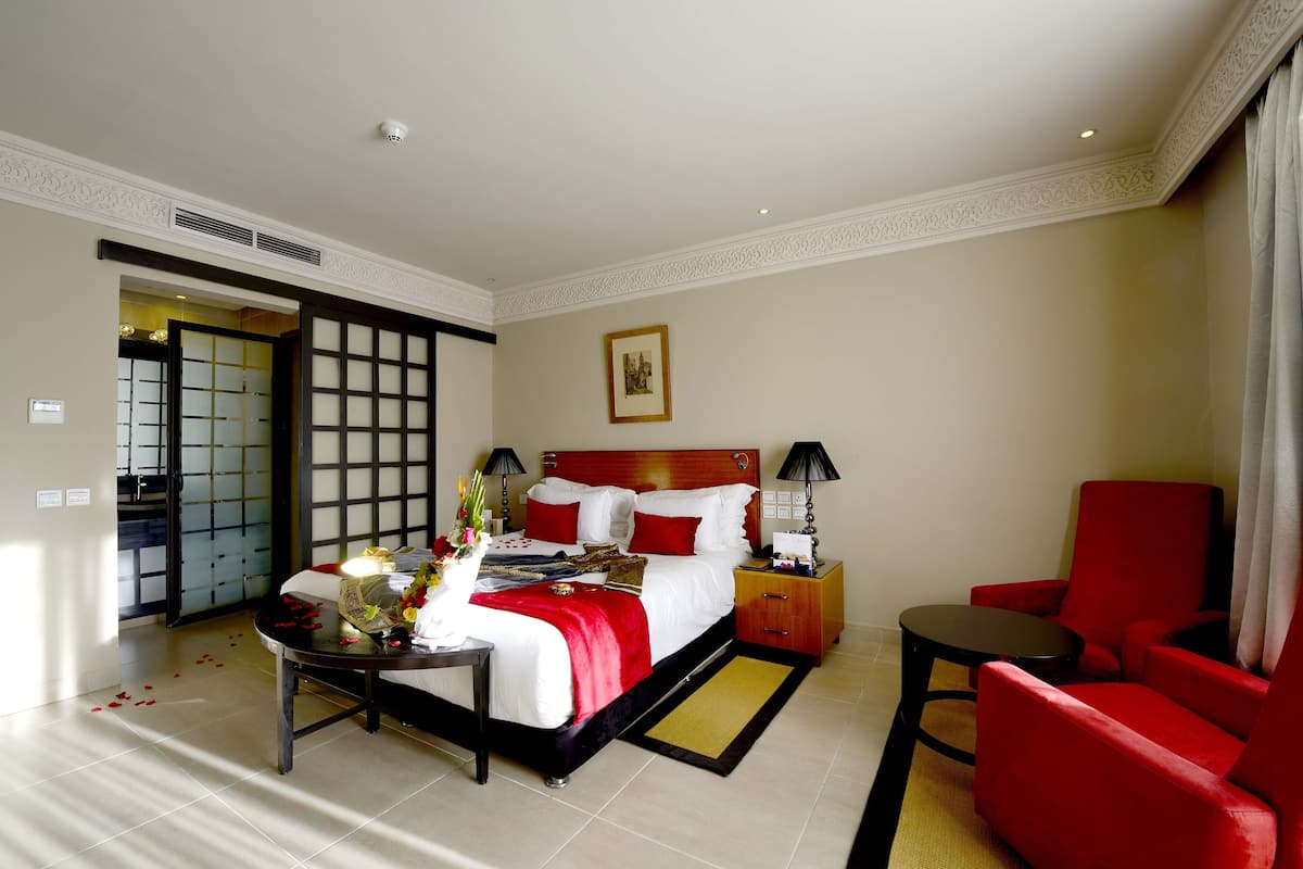 Une chambre d’hôtel avec un lit, un bureau, une chaise et une table de chevet.