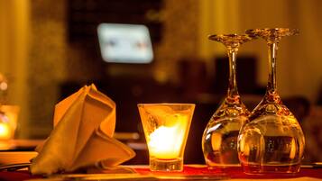 A bar setting with a candle, a napkin, and two glasses on a table.