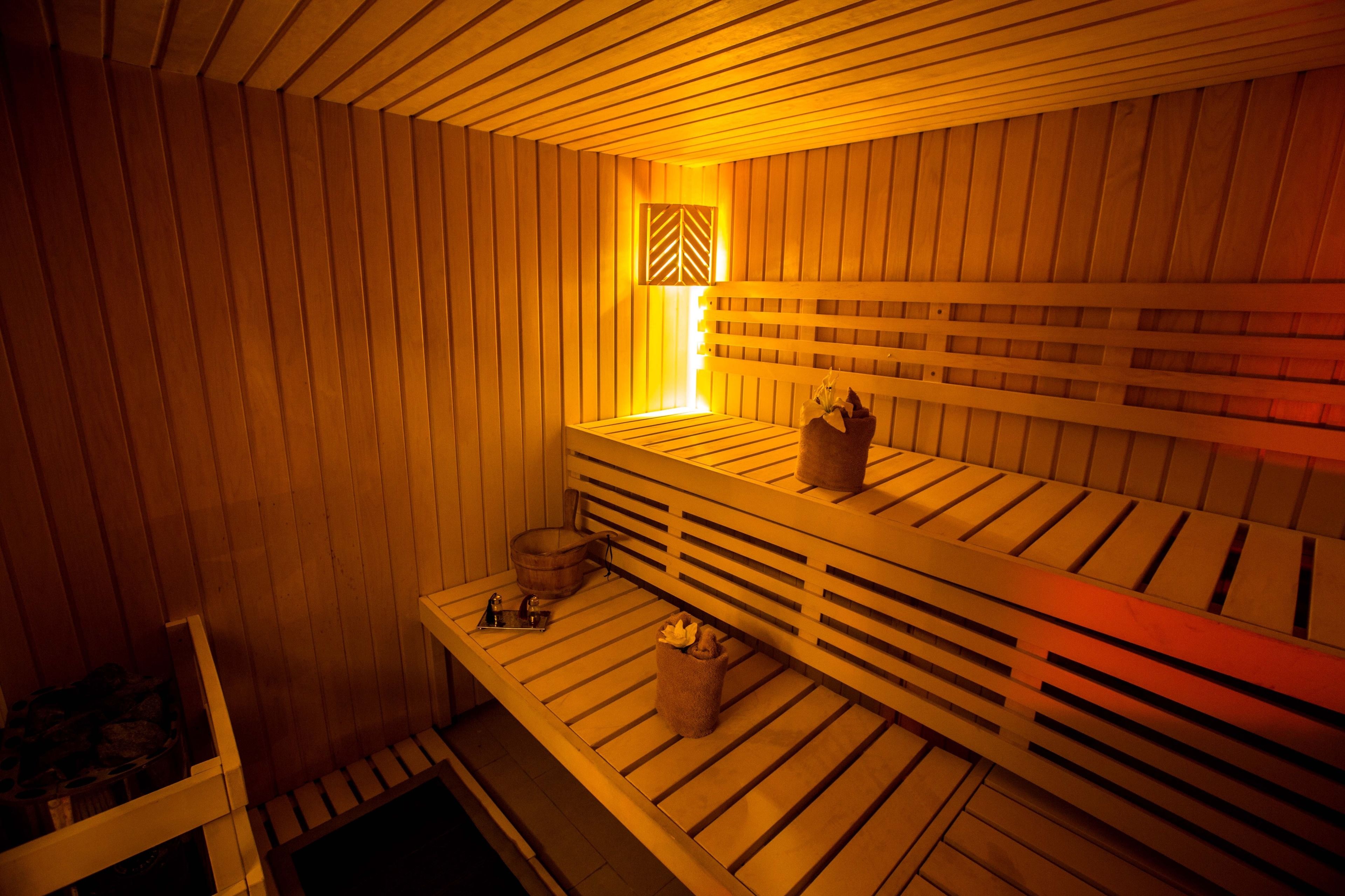 Eine Sauna mit Holzbänken, einer Sitzbank, einem Handtuchhalter und einem kleinen Tisch mit Handtuch und Flasche.