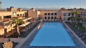 A large swimming pool surrounded by lounge chairs and umbrellas, with a view of mountains in the background. - Adam Park Hotel & Spa Marrakech (Marrakech)