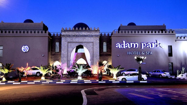 The exterior of Adam Park Hotel & Spa with a prominent archway, illuminated signage, and parked cars. - Adam Park Hotel & Spa Marrakech (Marrakech)