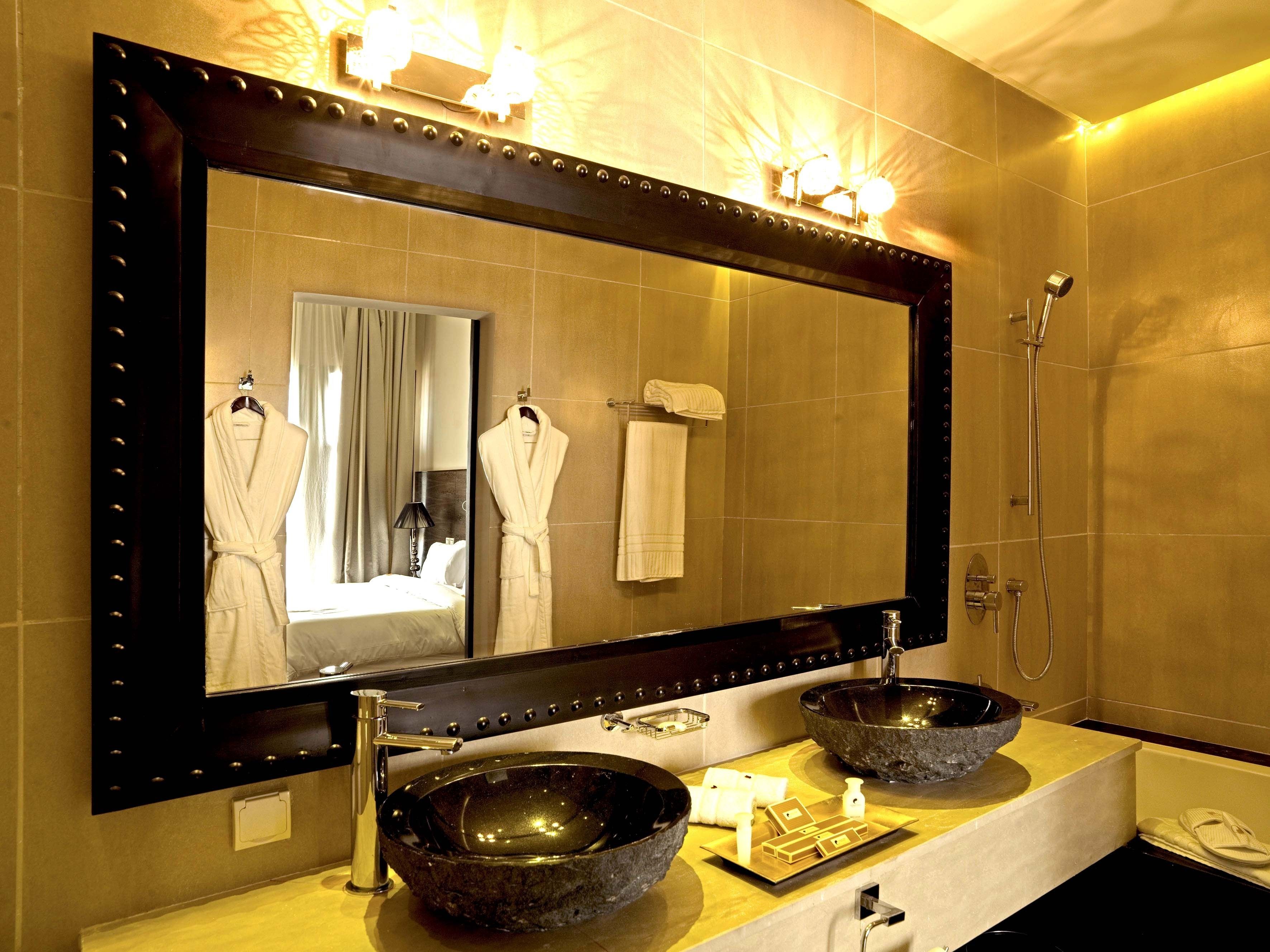 Een badkamer met een grote spiegel, twee wastafels en een douche.