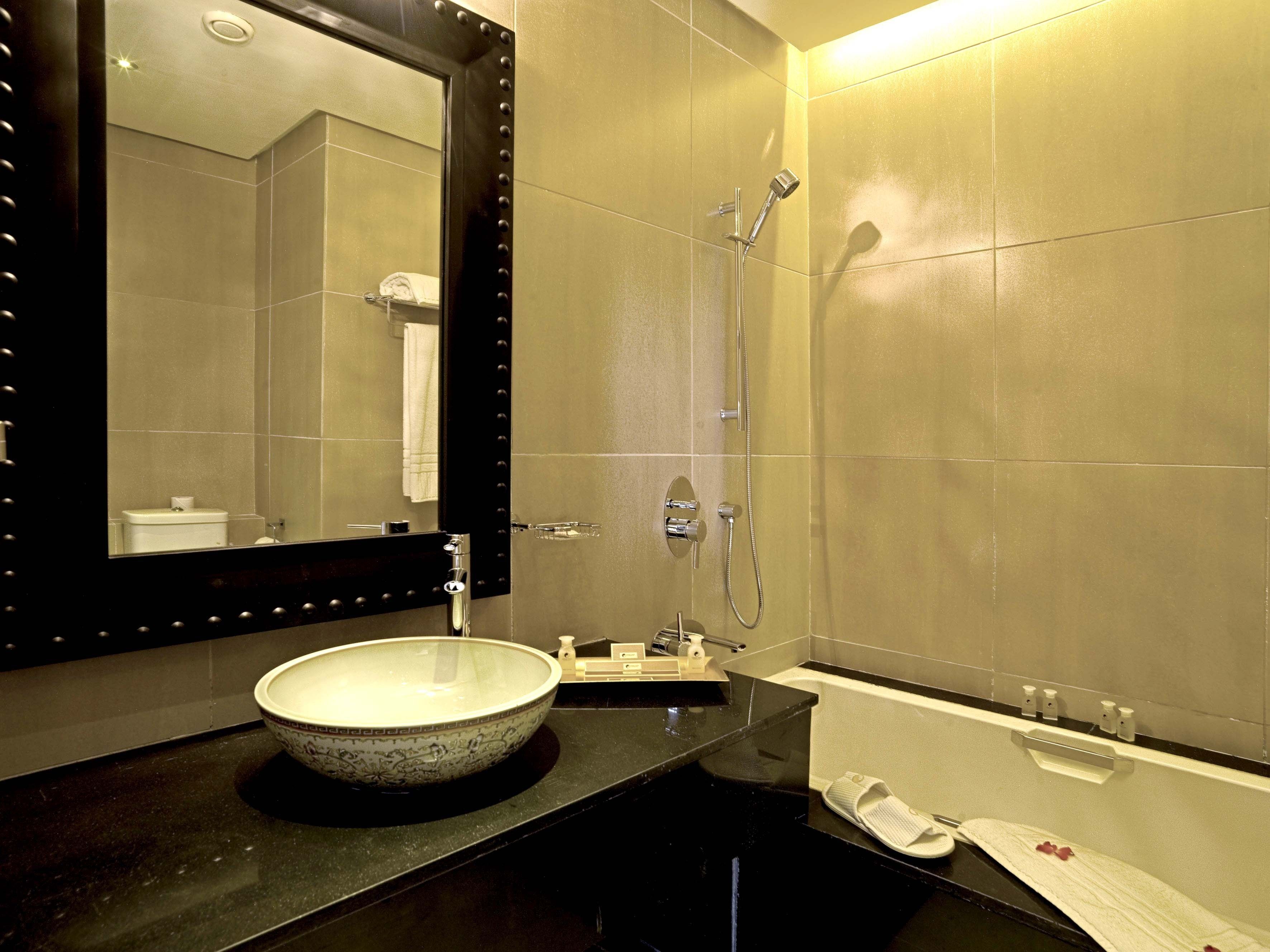 Un baño moderno con un espejo grande, un lavabo sobre encimera, una bañera y una ducha.