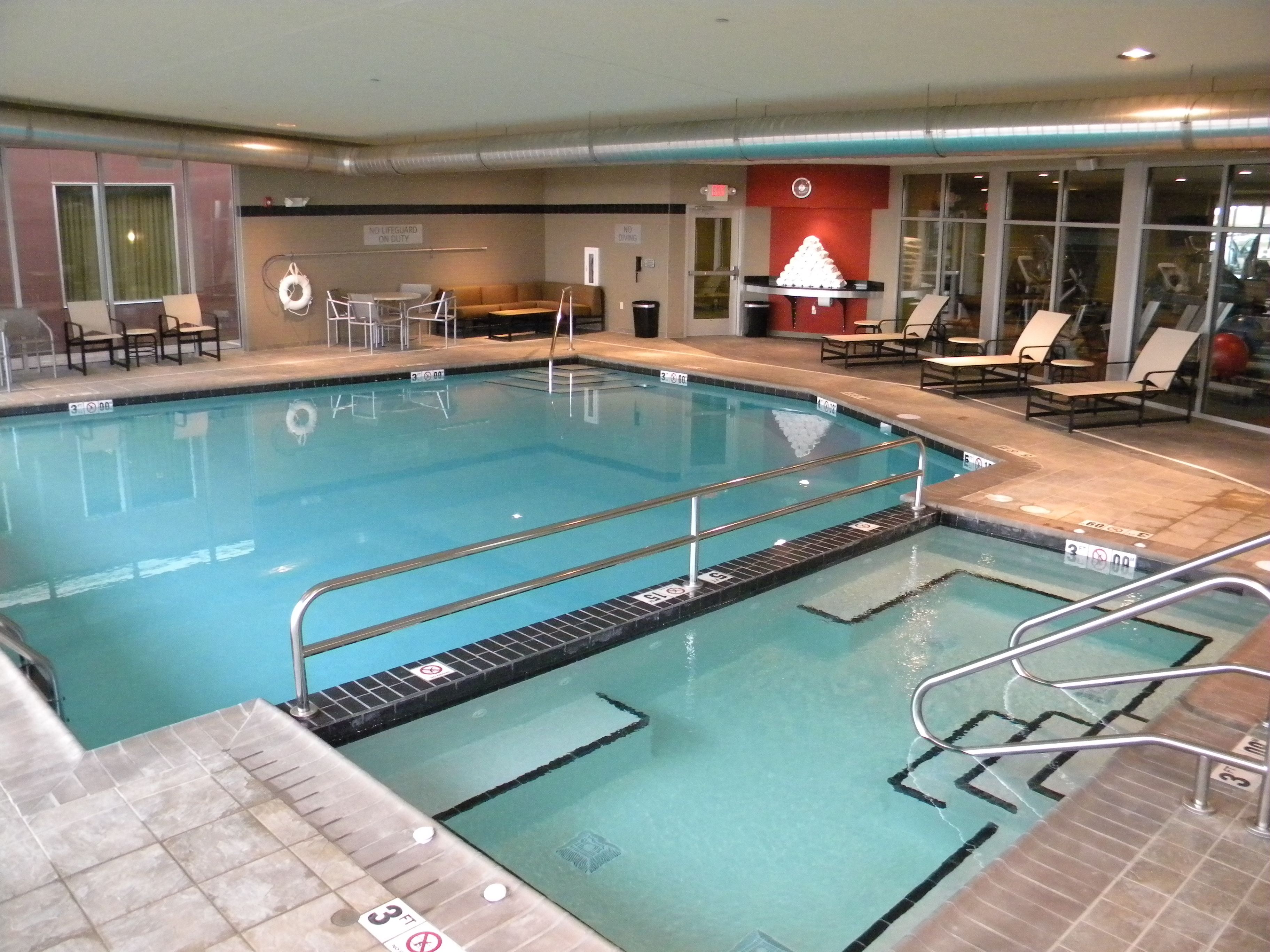 Una piscina interior con carriles claramente delimitados, sillas de descanso y una silla para socorrista.