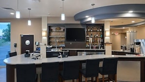 A modern kitchen with a bar area, a flat-screen TV, and a wine rack.