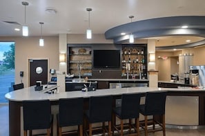 A modern kitchen with a bar area, a flat-screen TV, and a wine rack. - Cambria Hotel Rapid City near Mount Rushmore (Rapid City)