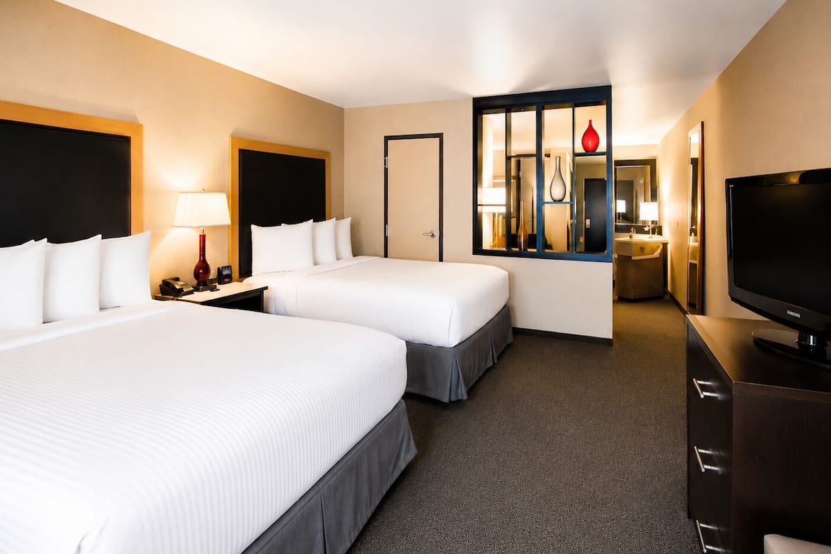 Une chambre d’hôtel avec deux lits, une télévision, un bureau et un miroir.