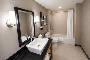 A bathroom with a sink, toilet, bathtub, and shower curtain. - Cambria Hotel Rapid City near Mount Rushmore (Rapid City)
