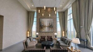 A spacious lobby with a stone accent wall, a large painting, and a seating area with sofas and a coffee table.