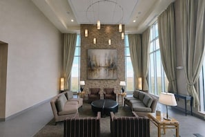 A spacious lobby with a stone accent wall, a large painting, and a seating area with sofas and a coffee table. - Cambria Hotel Rapid City near Mount Rushmore (Rapid City)