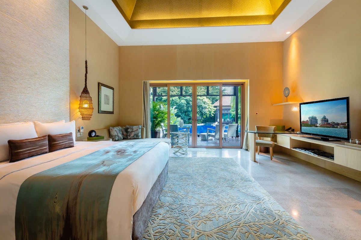 Une chambre d’hôtel moderne dotée d’un grand lit, d’une télévision et d’un balcon aménagé avec du mobilier d’extérieur.