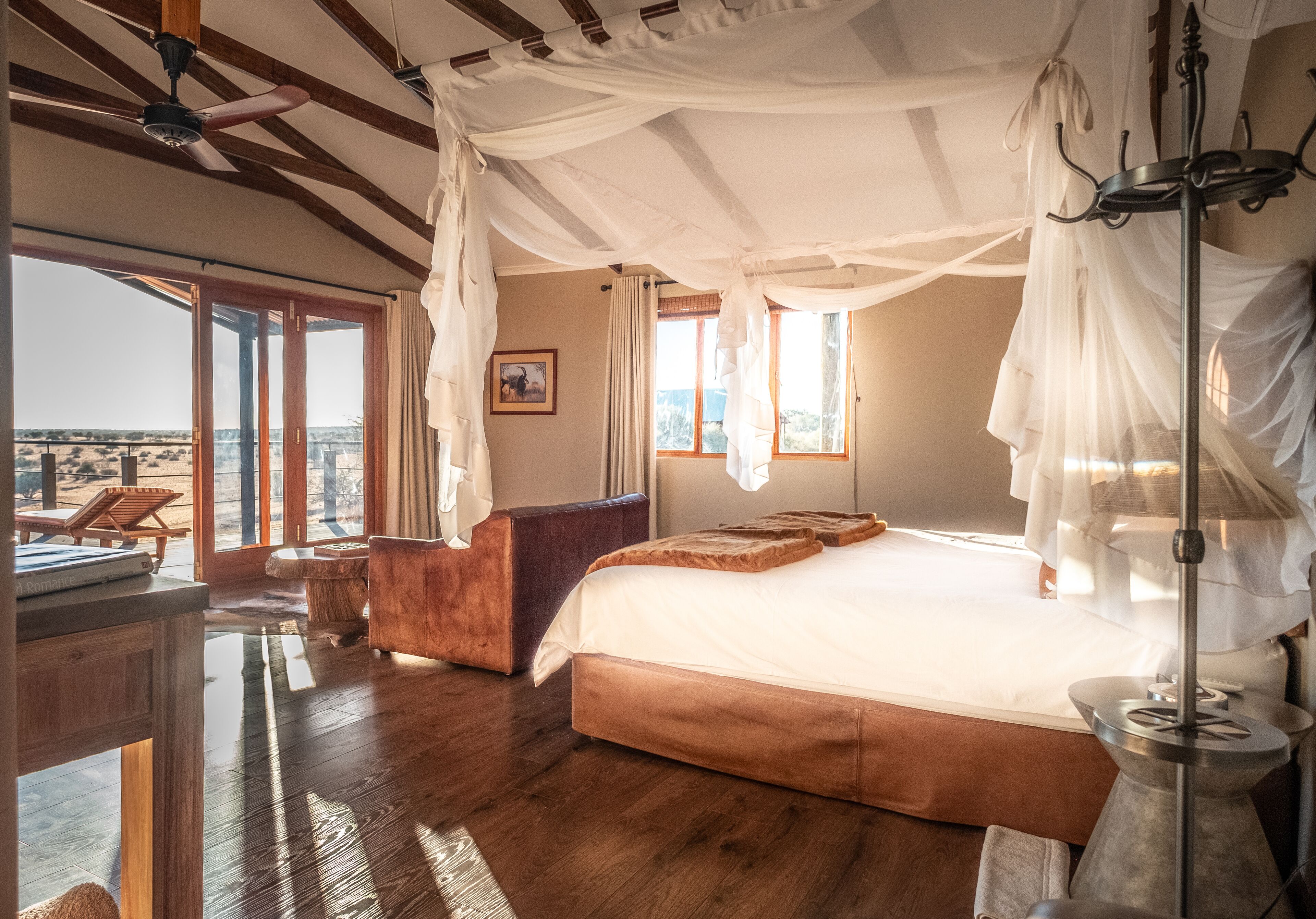 Un dormitorio con una cama grande, una mesita de noche, una silla y vistas al exterior.