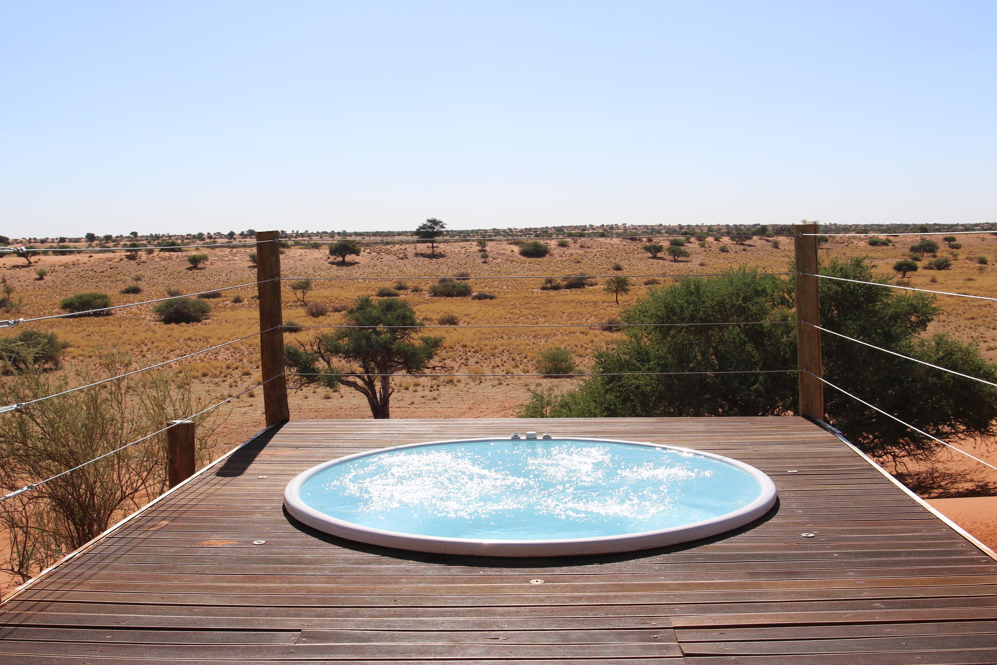 Une piscine extérieure située sur une terrasse en bois, offrant une vue sur un paysage désertique.