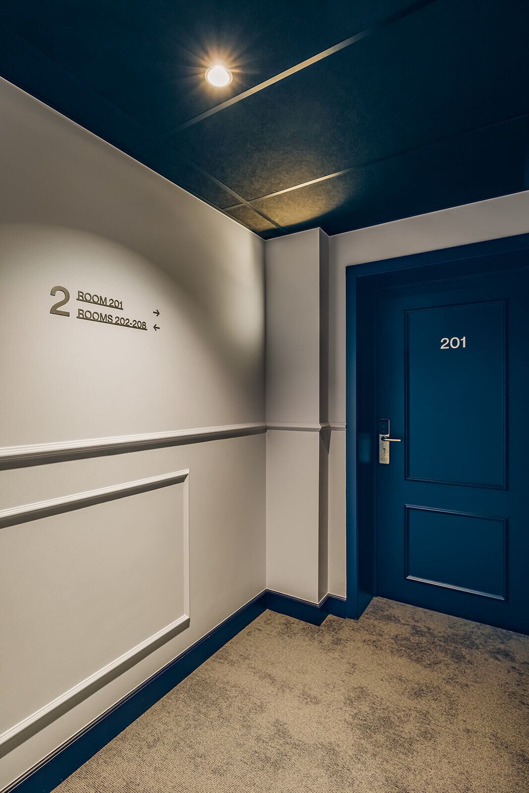 Ein Flur mit einem Schild, das 'ZIMMER 201' und 'ZIMMER 202-208' ausweist.
