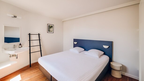 A bedroom with a bed, a bedside table, a mirror, a sink, and a toilet. - ROMY BRUGES Historic Centre (Bruges)