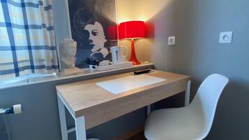 A small room with a desk, chair, and a window with curtains.