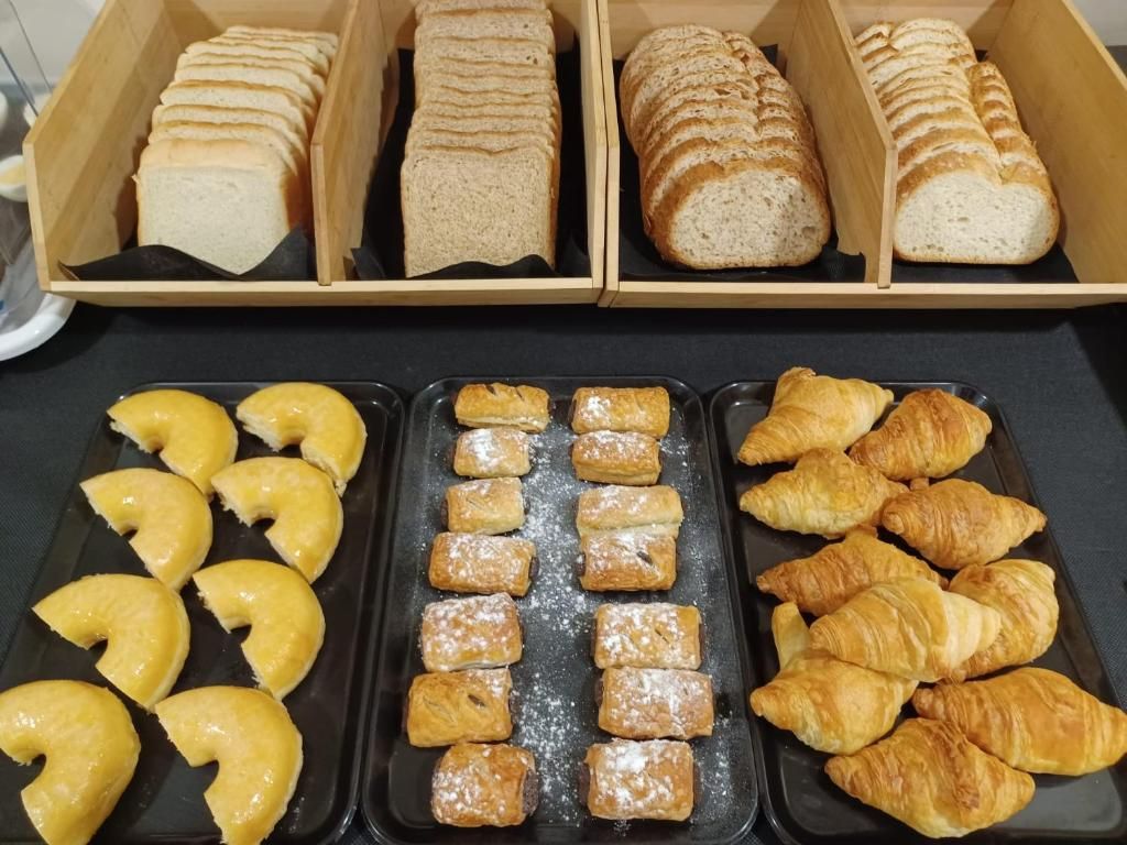A variety of baked goods including bread and pastries arranged on trays.