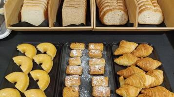 Une variété de produits de boulangerie, notamment du pain et des pâtisseries, disposés sur des plateaux.