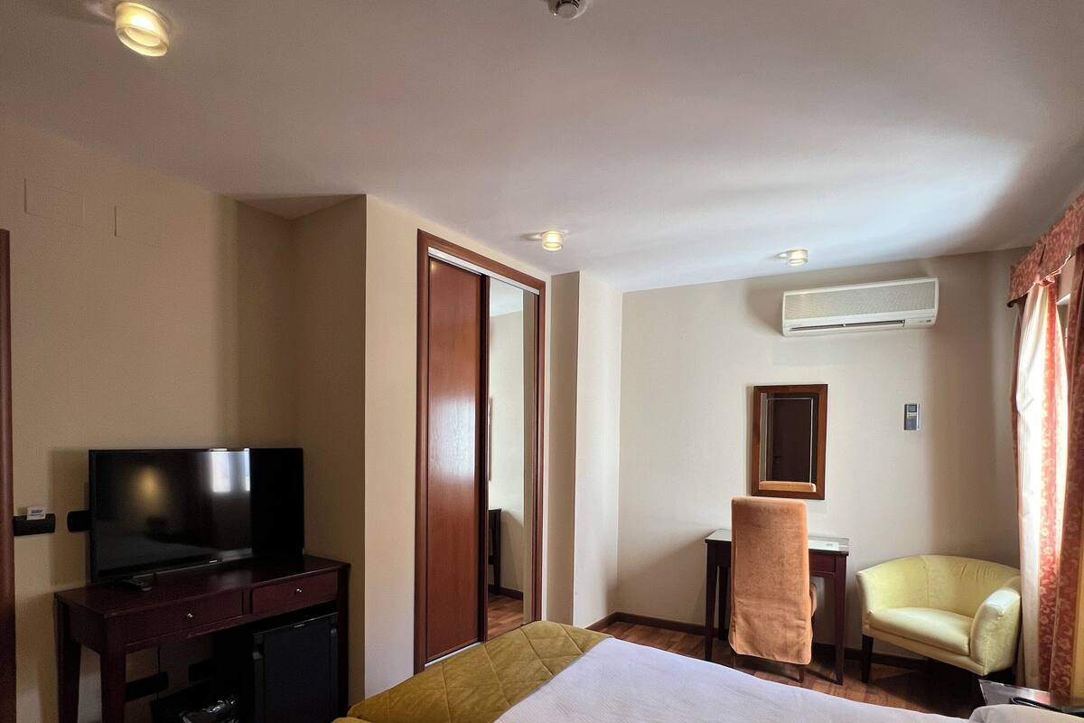 Une chambre d’hôtel avec deux lits, une télévision, un bureau, une chaise et un appareil de climatisation.