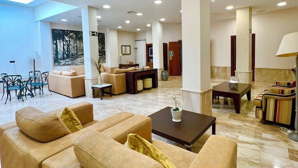 Un vestíbulo amplio con varias zonas de estar, incluyendo sofás y sillones, además de un comedor con mesa y sillas.