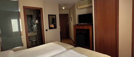 Una habitación de hotel con una cama grande, un escritorio, un espejo y un armario.
