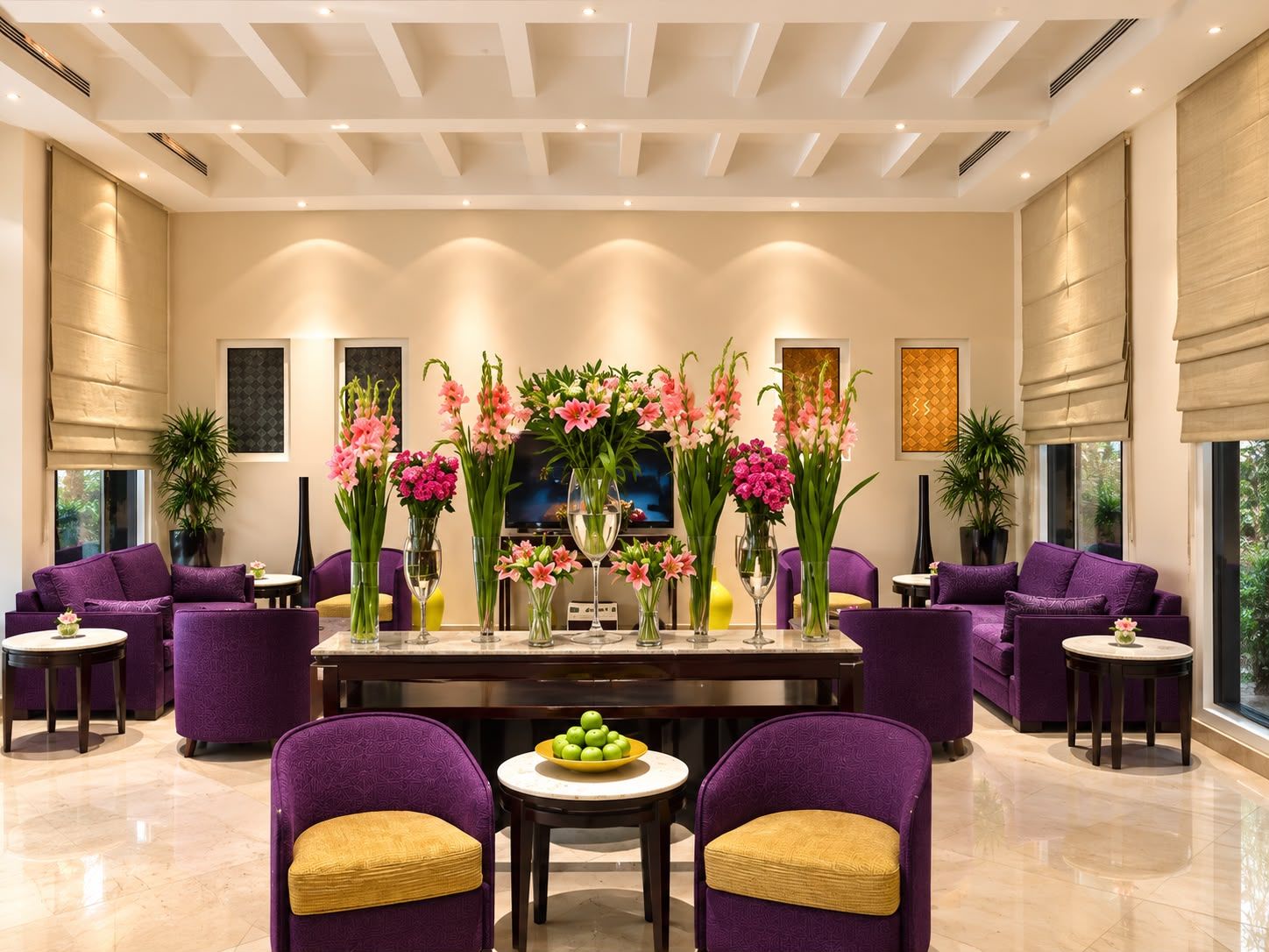 A modern lobby with a reception desk, purple seating, and floral arrangements.