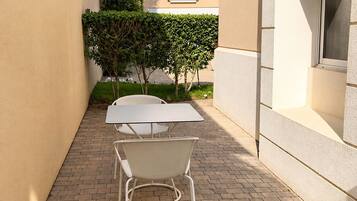 A patio with a white table and chairs, surrounded by a brick floor and beige walls.