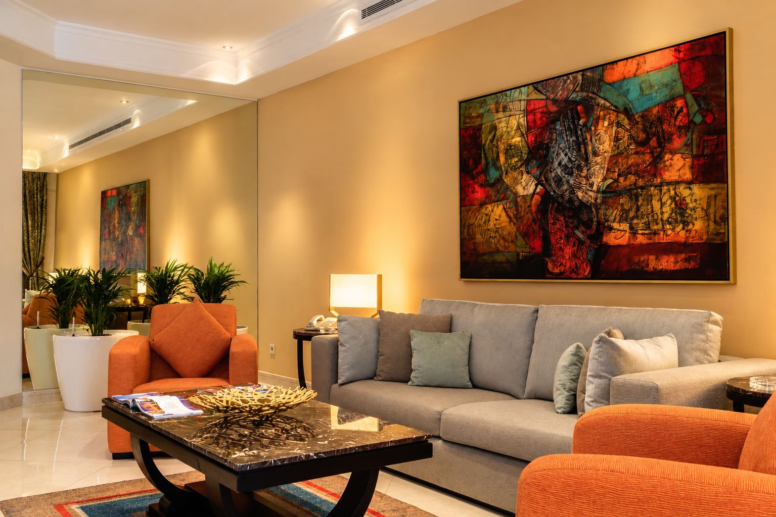 A modern living room with a sofa, armchairs, a coffee table, and a large abstract painting.