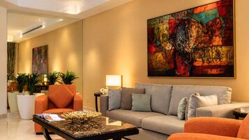 A modern living room with a sofa, armchairs, a coffee table, and a large abstract painting.