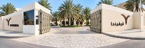 A gated entrance with palm trees and a paved pathway leading to a building with the name 'VIMENDA' on the wall. - Vivienda Hotel Villas, Turki Al Awwal (Riyadh)