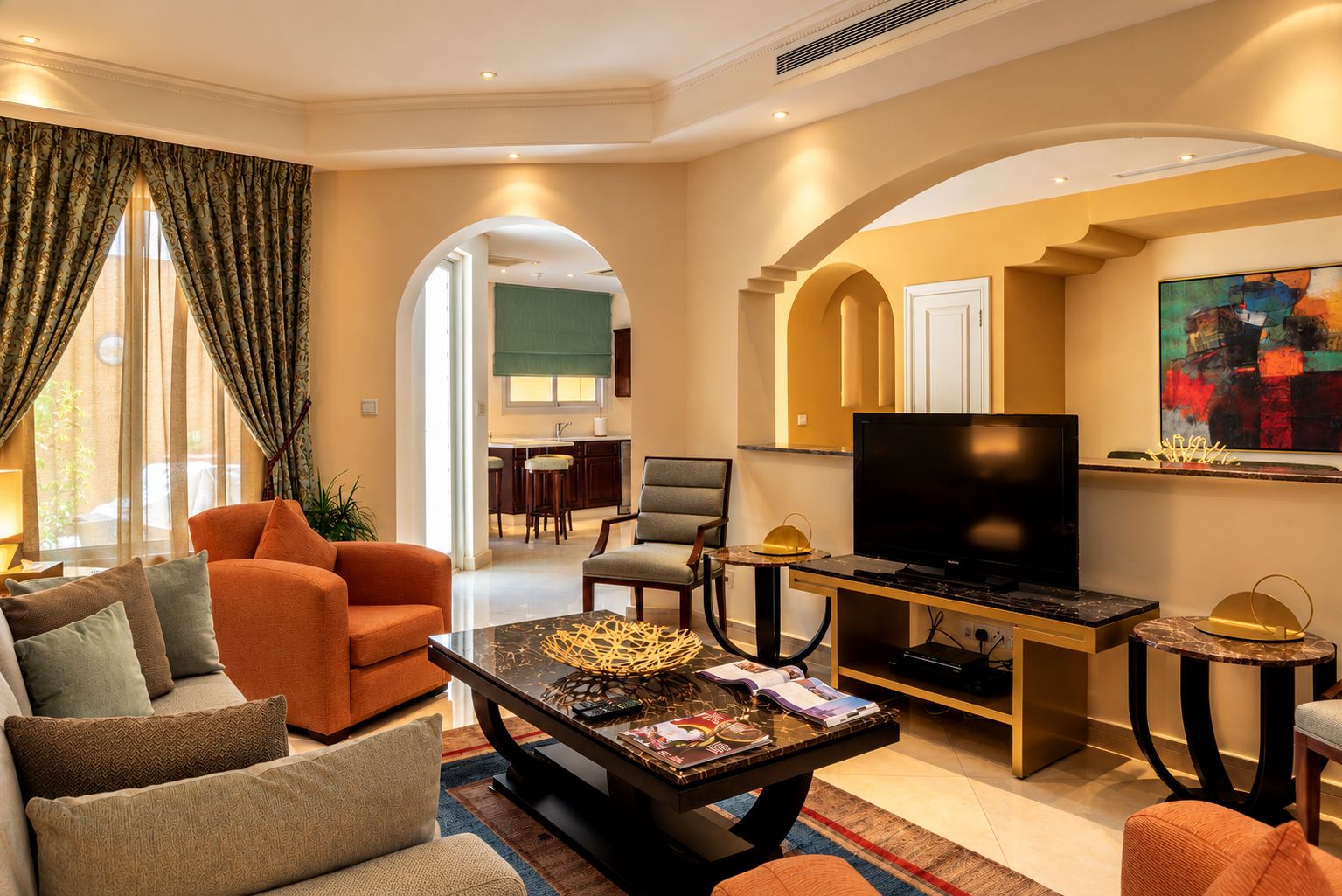 A modern living room with a sofa, armchairs, a coffee table, and a television.