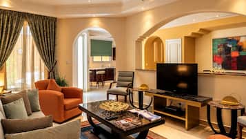 A modern living room with a sofa, armchairs, a coffee table, and a television.