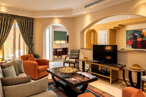 A modern living room with a sofa, armchairs, a coffee table, and a television.