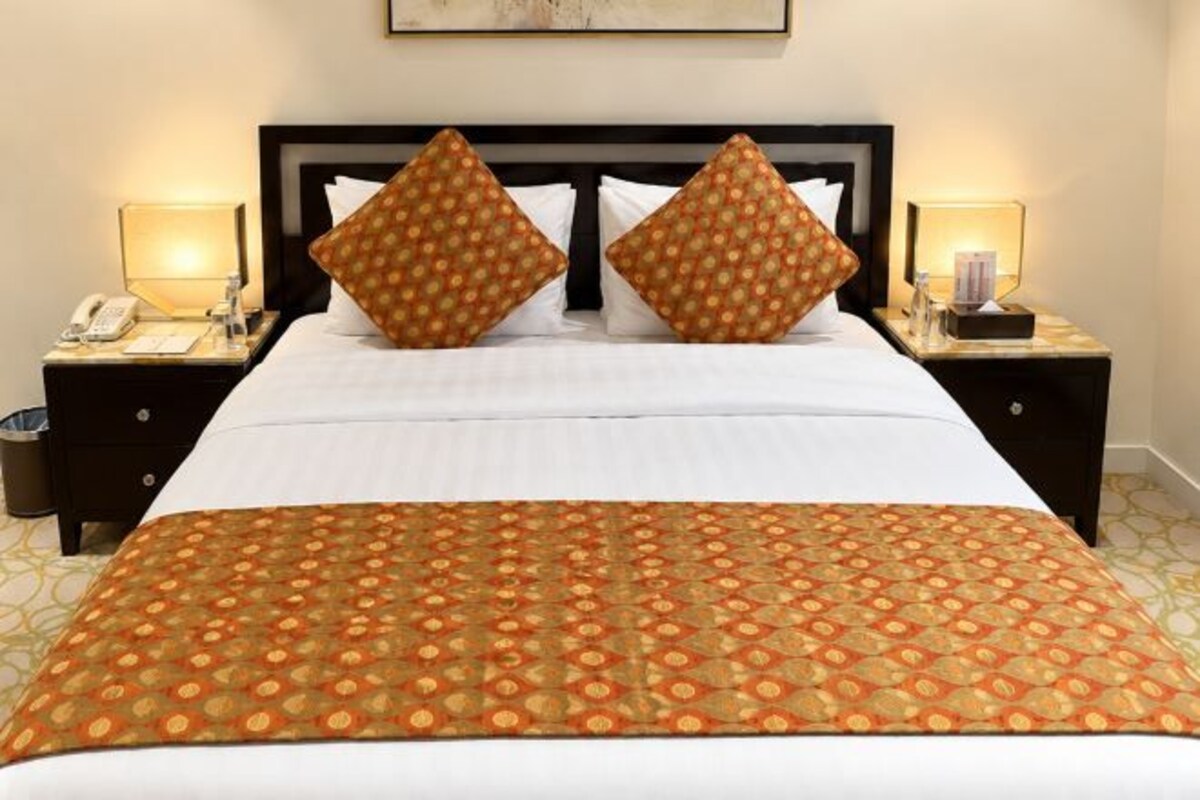 A hotel room with a large bed, two nightstands, and a patterned bedspread.