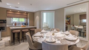 Een moderne eethoek met een marmeren tafel, barkrukken en een keuken op de achtergrond.