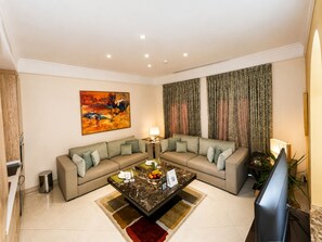 A modern living room with a sectional sofa, a glass coffee table, and a flat-screen TV. - Vivienda Hotel Villas, Turki Al Awwal (Riyadh)