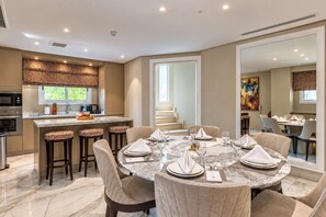 A modern dining area with a marble table set for six, surrounded by cushioned chairs. - Vivienda Hotel Villas, Turki Al Awwal (Riyadh)