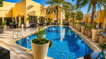 A pool area with a tiled floor, surrounded by lounge chairs and potted plants.