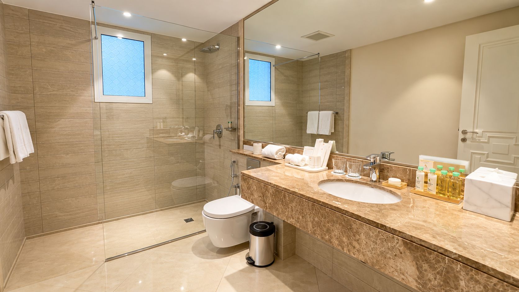 A modern bathroom with a glass-enclosed shower, a white toilet, and a marble sink.