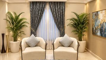 A spacious living room with a large coffee table, two sofas, and potted plants.