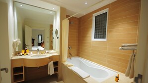 Een moderne badkamer met dubbele wastafels, een ruime badkuip en een spiegel.