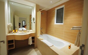 A modern bathroom with dual sinks, a large bathtub, and a mirror.