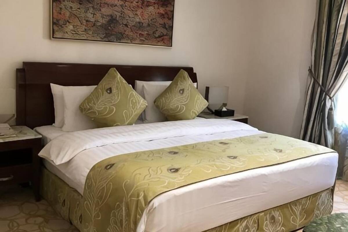Ein Hotelzimmer mit einem großen Bett, einem Nachttisch, einer Lampe und einem Bild an der Wand.