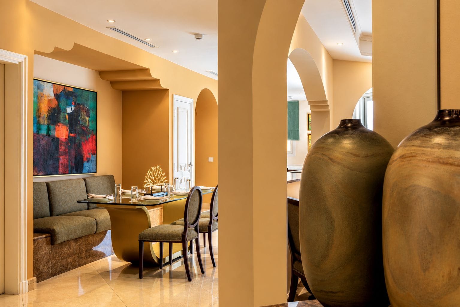A modern interior with a dining area, a sofa, and a large abstract painting.