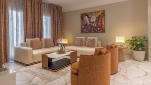Een moderne woonkamer met een bank, fauteuils, een salontafel en een schilderij aan de muur.